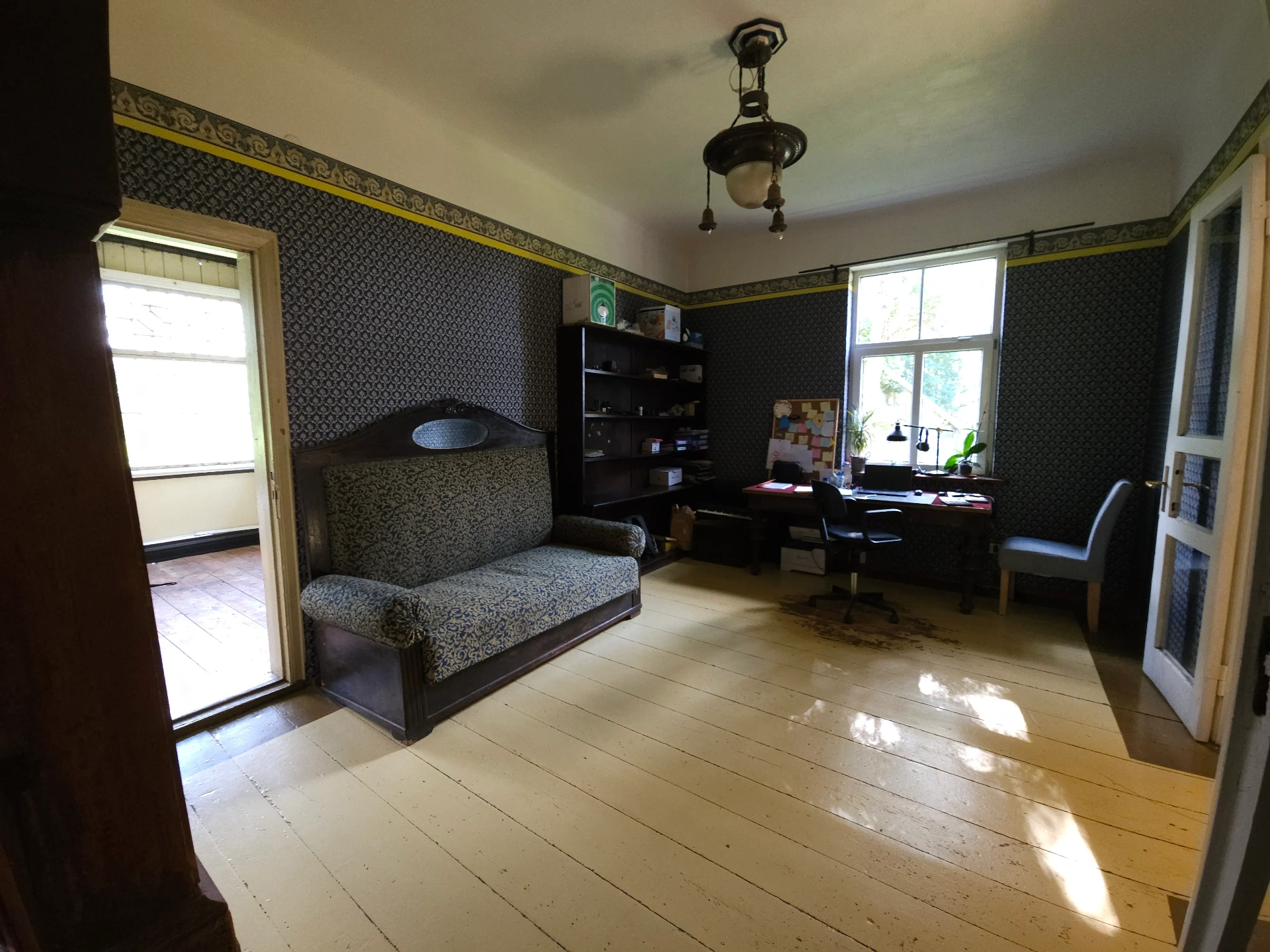 Study room with patterned wallpaper, antique sofa and desk area