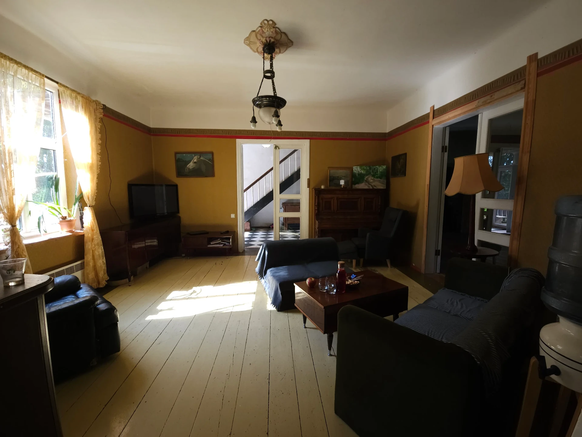 Living room with yellow walls and vintage furniture, featuring wooden floors and art deco elements