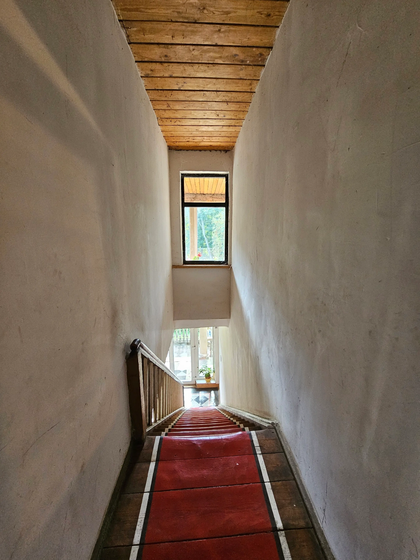 Historic staircase with red carpet runner and white walls